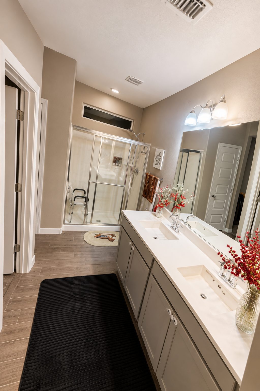 Accessible bathroom with a walk-in shower, grab rail, shower chair and a wide double vanity