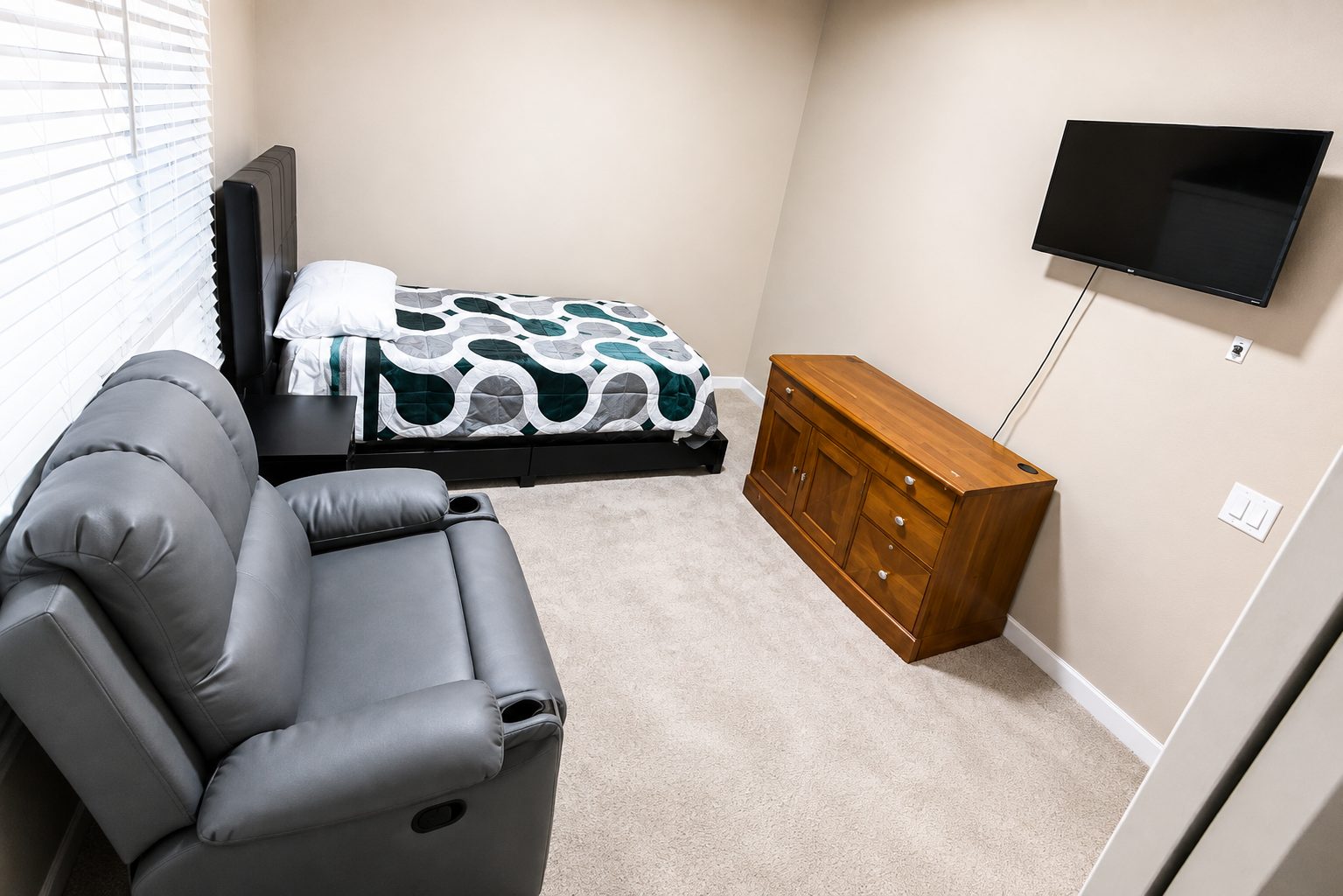 A private resident room at Agape Home with a bed, recliner, dresser and television