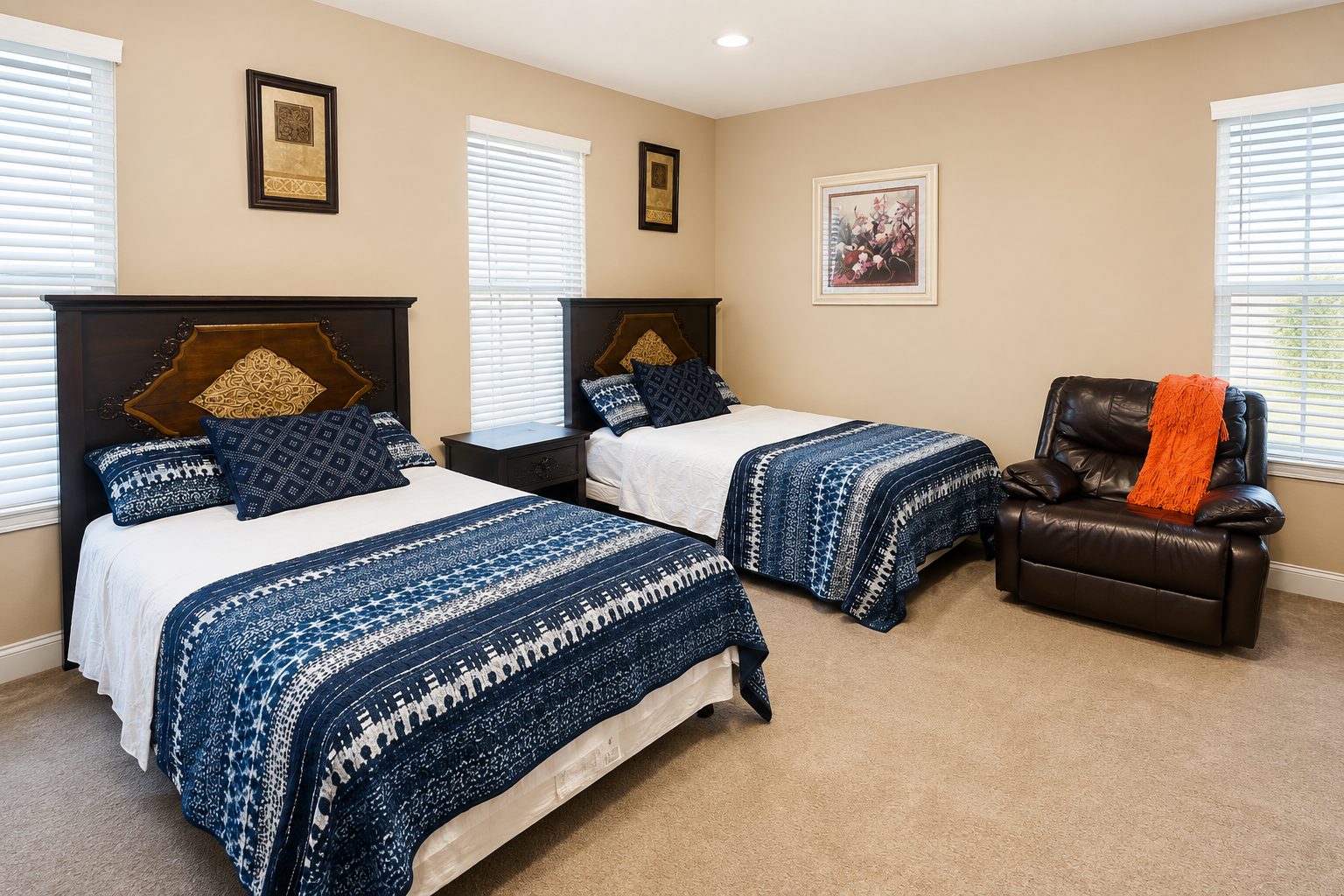 Shared resident room with two made beds, bedside table and a recliner beside the window